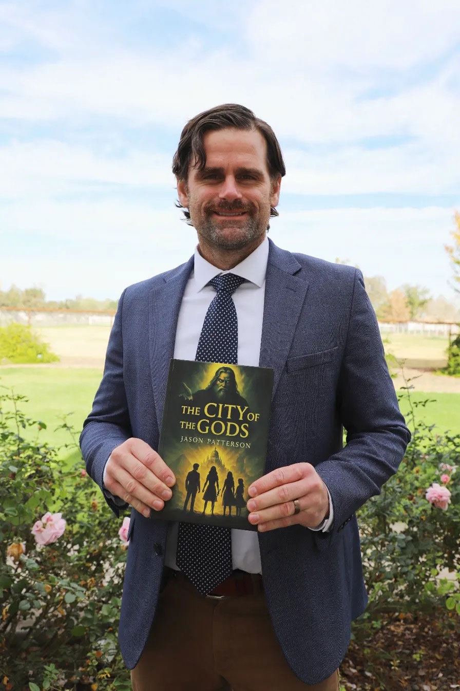 Jason Patterson holding his published book The City of the Gods